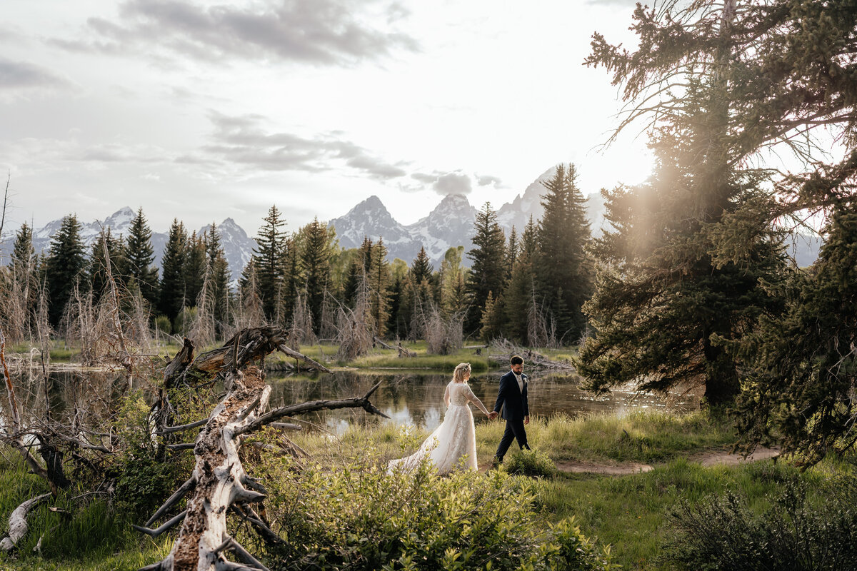 A couple walks in front of a sunset in Grand Teton National Park.