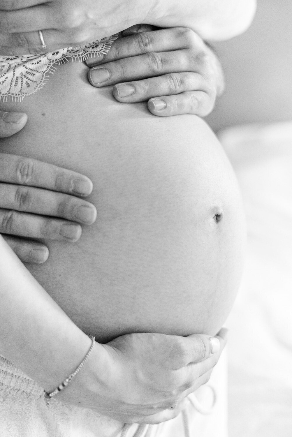 Zwart wit zwangerschapsfoto van een zwangere buik met de handen van de ouders. Irene Maris Fotografie 