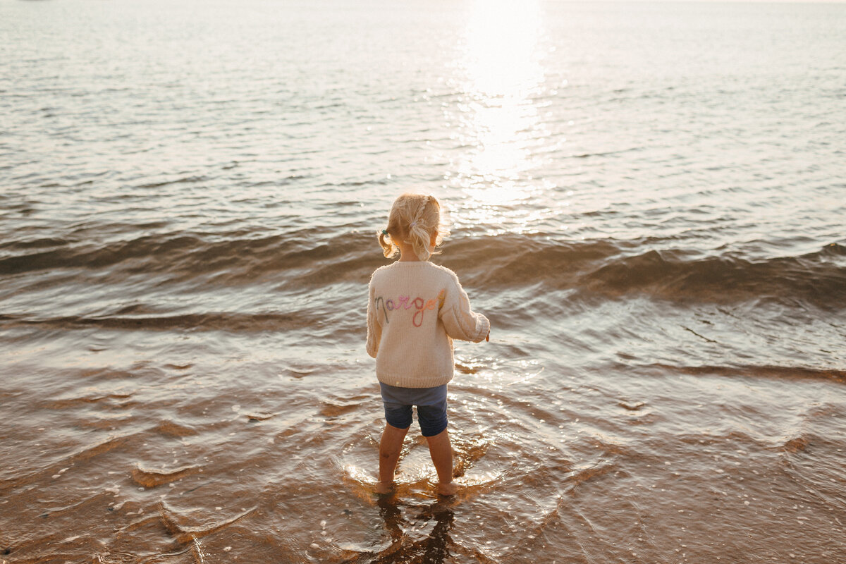 Young girl paddles in the sea at sunset