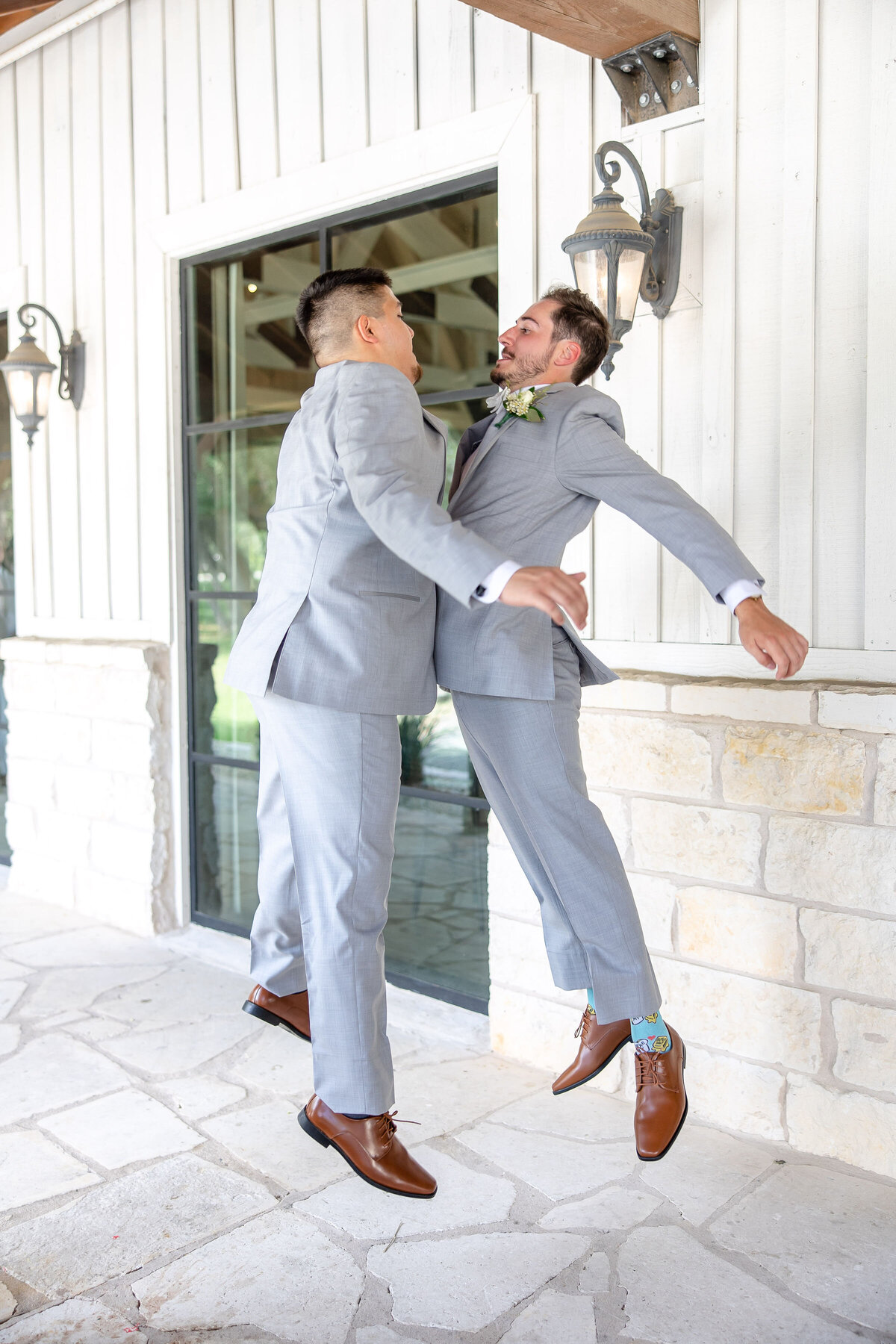 groom and groomsman chest bump in gray suits at Austin wedding