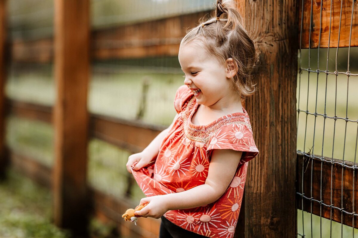 Young girl smiling brightly during a family photo session at Bellevue’s Kelsey Creek Farm, full of joy and charm.