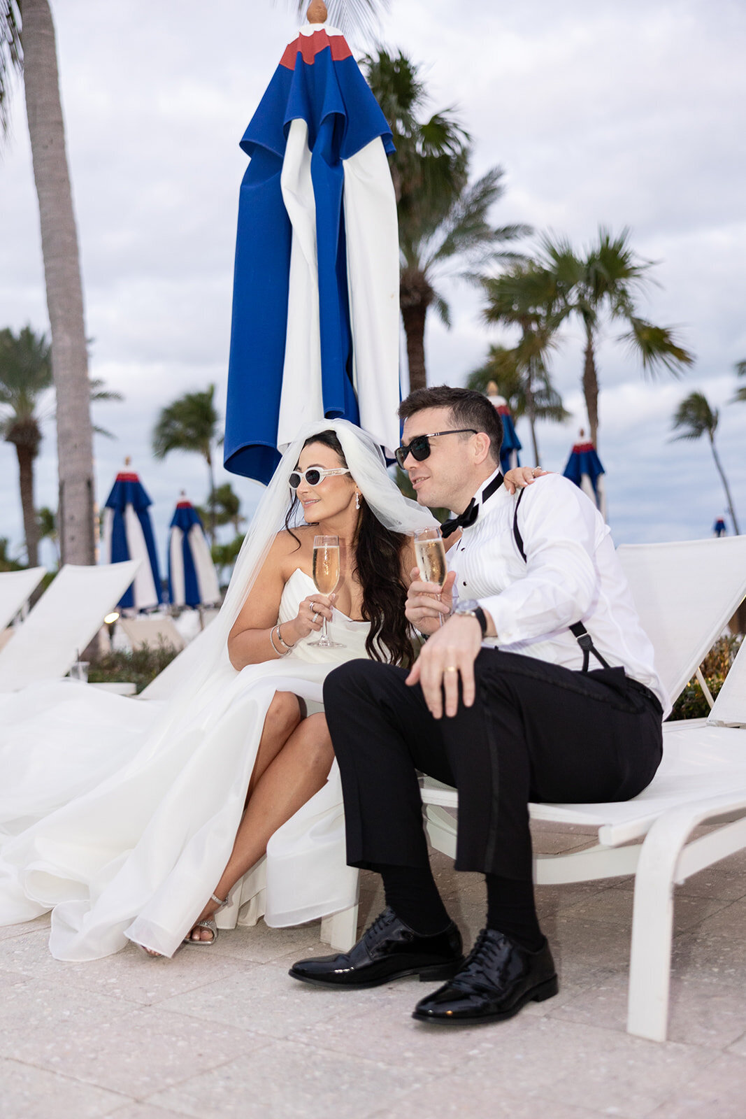 The bride and groom relax by the poolside with champagne, celebrating their wedding day at Ocean Reef in Key Largo.