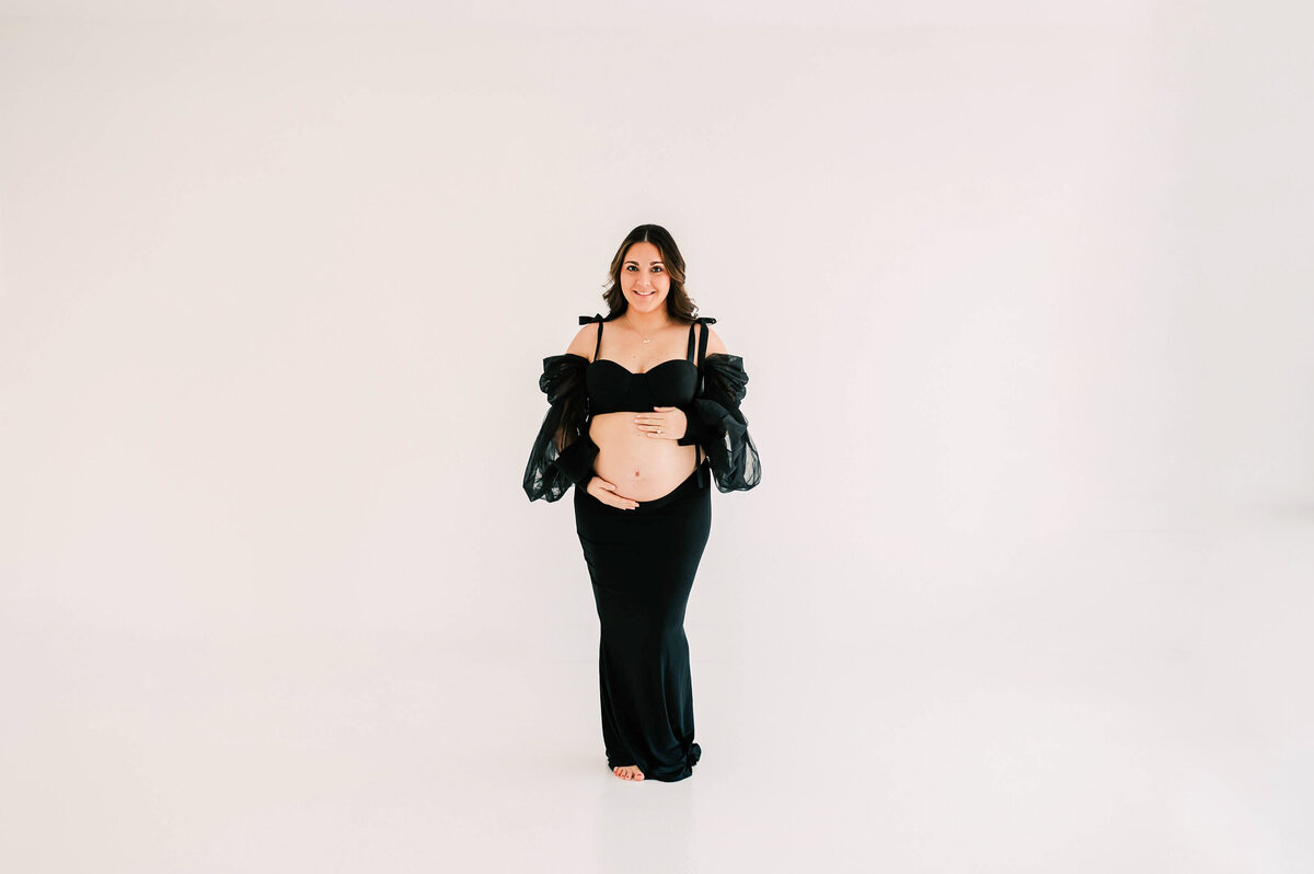 pregnant mom in black dress holding bare belly bump