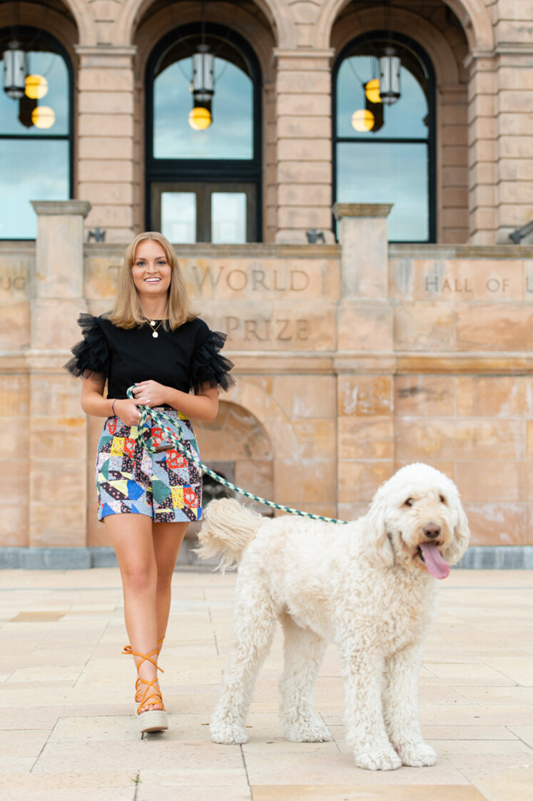 Senior girl walking with a white dog in an urban area, stylish and confident.