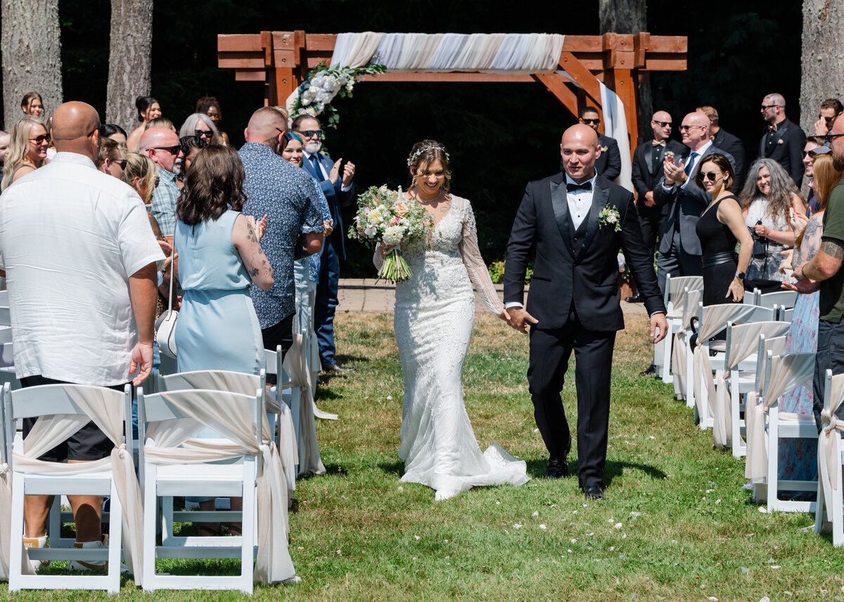 just married wedding bride and groom walk down the aisle in sun