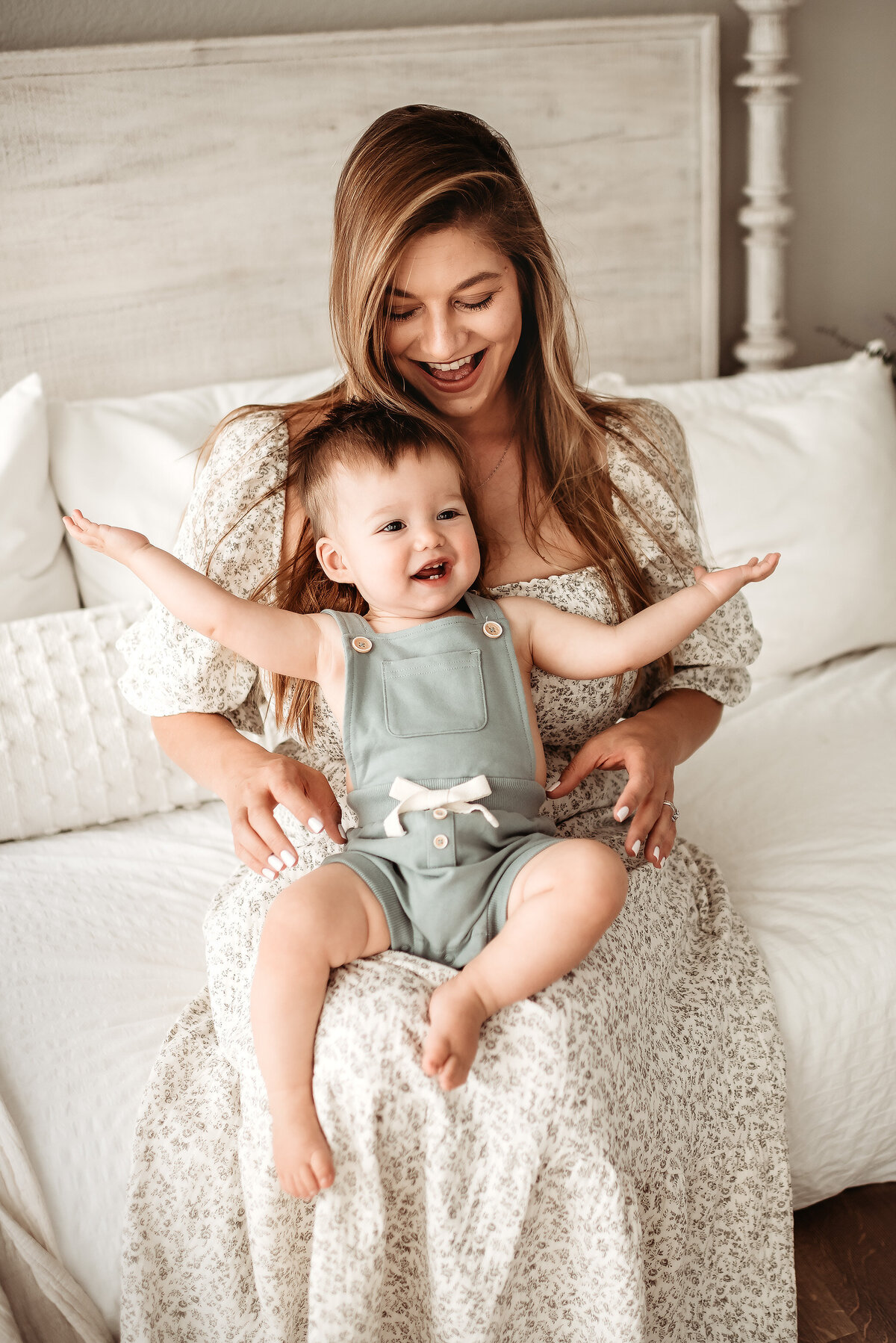 baby boy sitting with his mom with his arms outstretched during milestone photo session