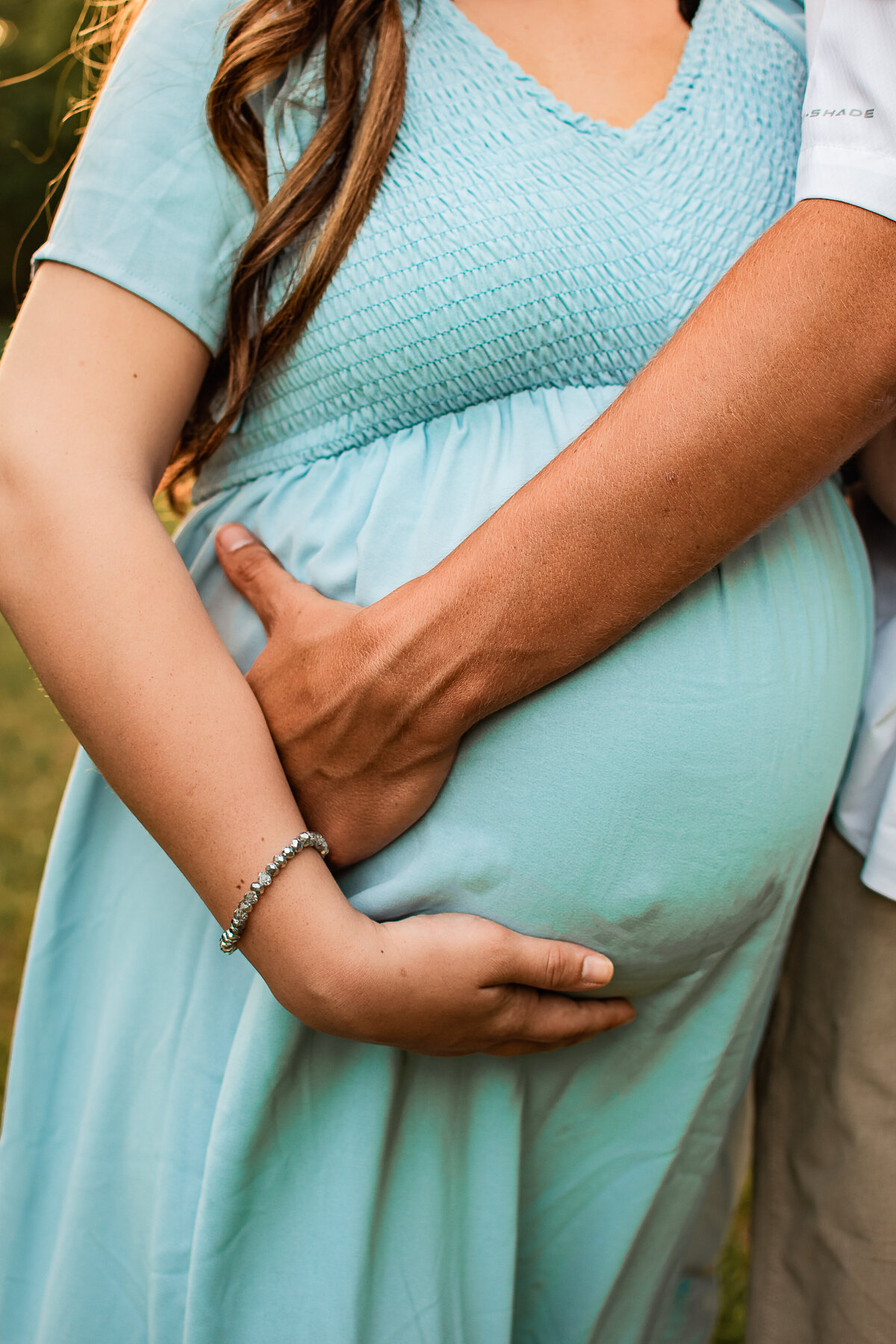 A close up shot of a couple holding their baby bump.