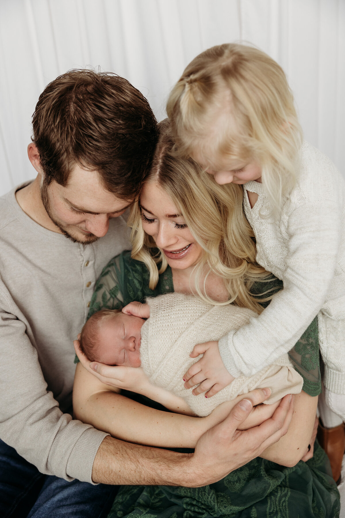 family of four in cream and green  with baby wrapped in cream wrap