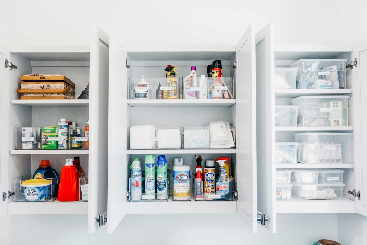 A laundry room with open cabinets revealing organized cleaning products