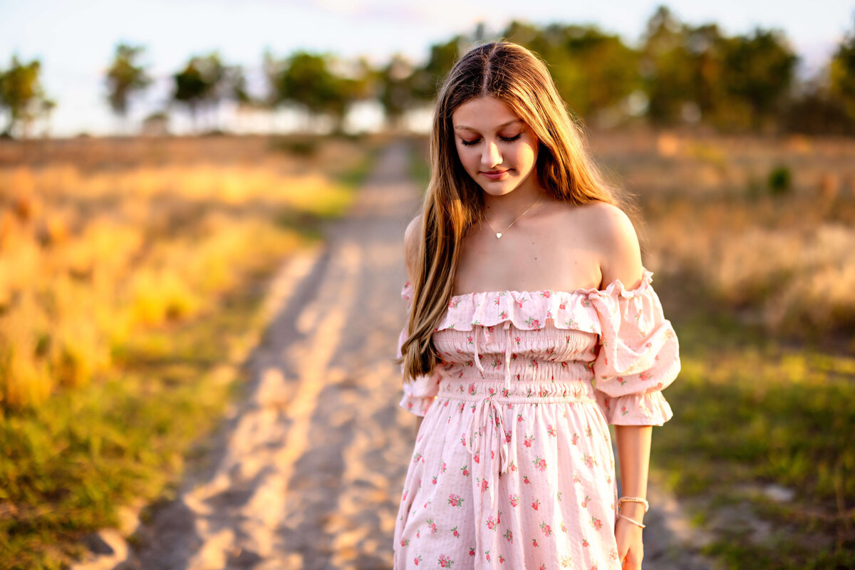 Senior girl walking in boots through field trail during golden hour in Winter Garden, Florida