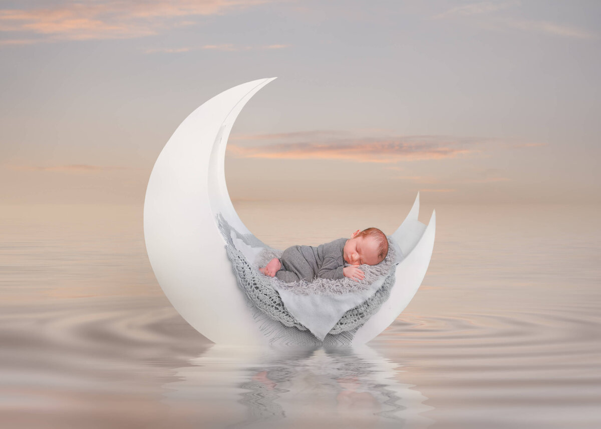 Composite by photographer E. Benecki Photography of a newborn sleeping on his tummy on a crescent moon  floating on water.
