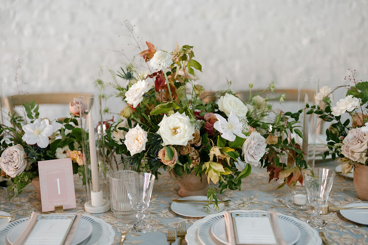 Fall reception table floral arrangements in colors of mauve, cream, dusty rose, dusty blue, taupe, and natural green. Autumn floral consisting of roses, rain tree pods, fall branches, clematis, and greenery. North Carolina wedding design by Rosemary and Finch floral design based in Nashville, TN.