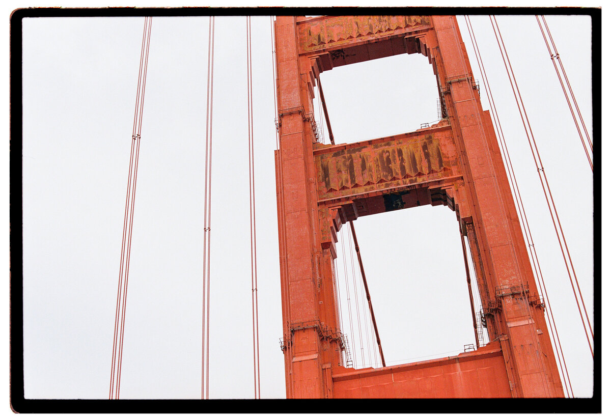 Side angle of the Golden Gate Bridge in San Francisco under an overcast sky, showcasing the bridge’s span disappearing into the fog