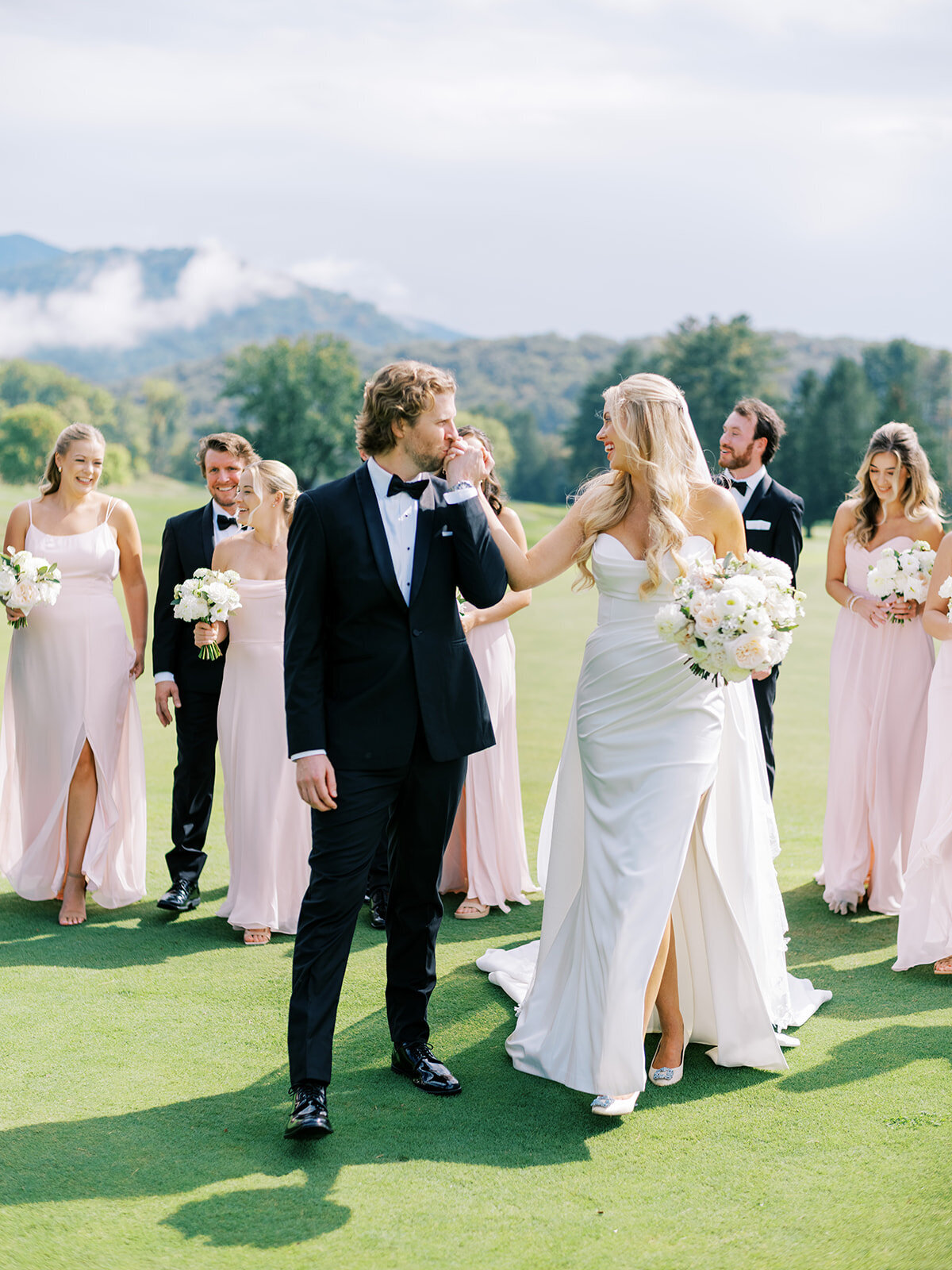 Bride, groom, bridesmaids, and groomsmen walking together across the golf course at The Waynesville Inn & Golf Club wedding in Waynesville, NC.