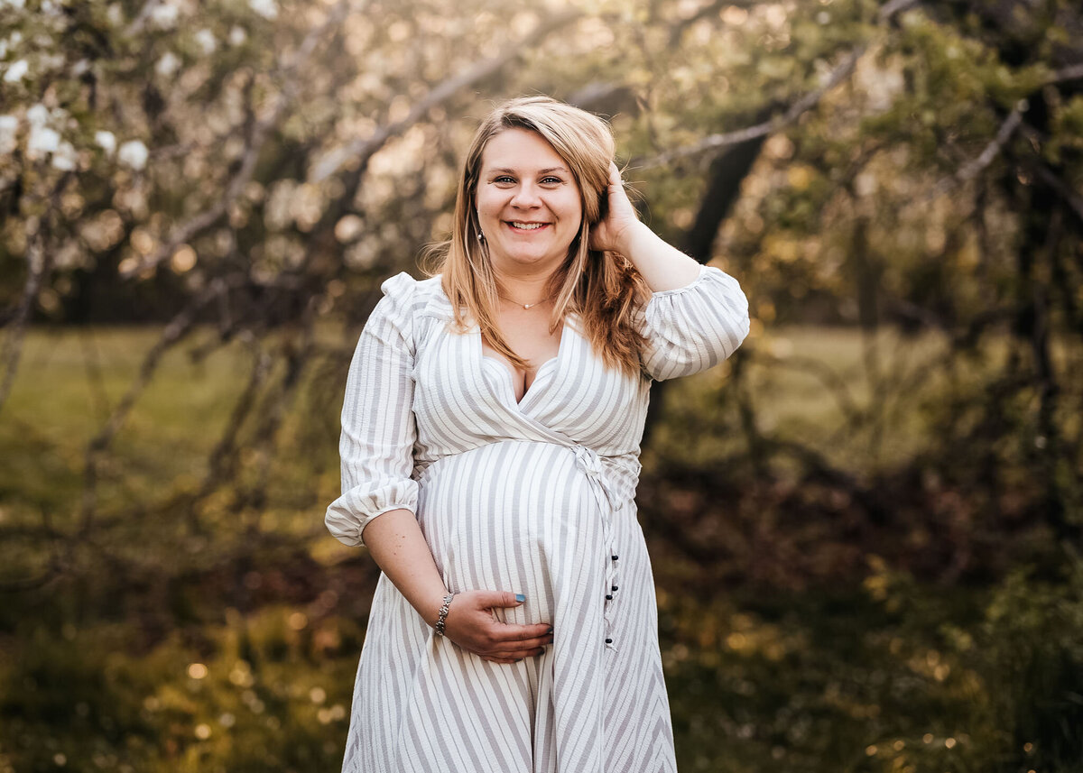 Expecting mother holding her belly at spring maternity photo session at Carey Cottage in Portsmouth NH by Lisa Smith Photography