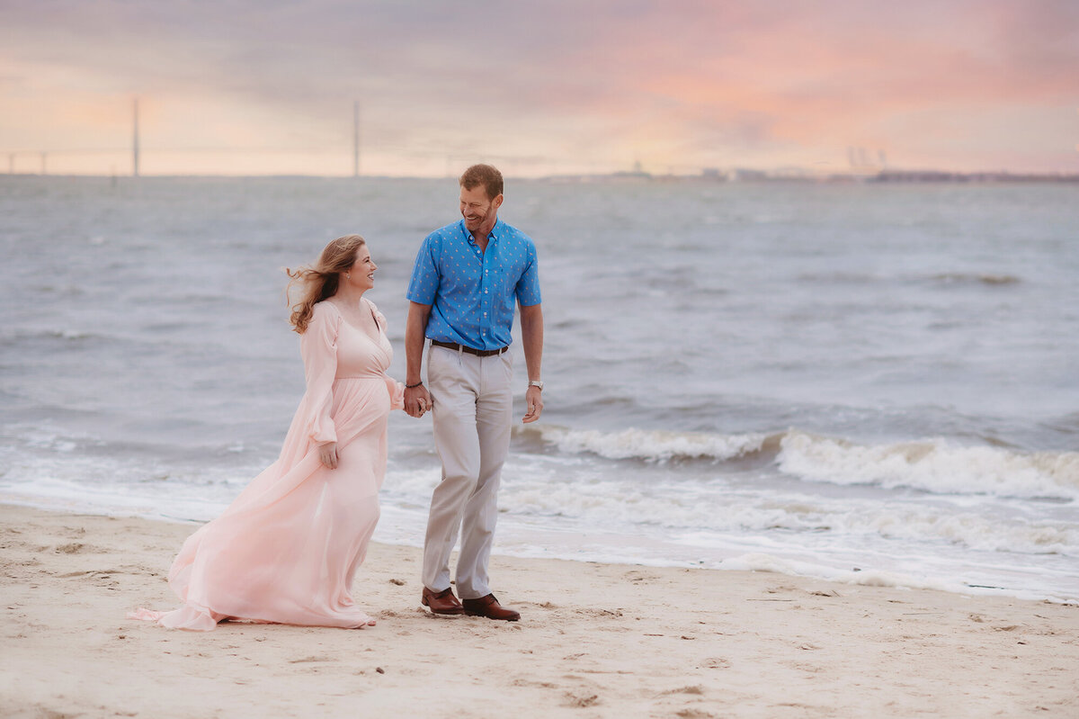 Expectant parents walk hand in hand along the beach in Charleston , South Carolina during Maternity Photoshoot.