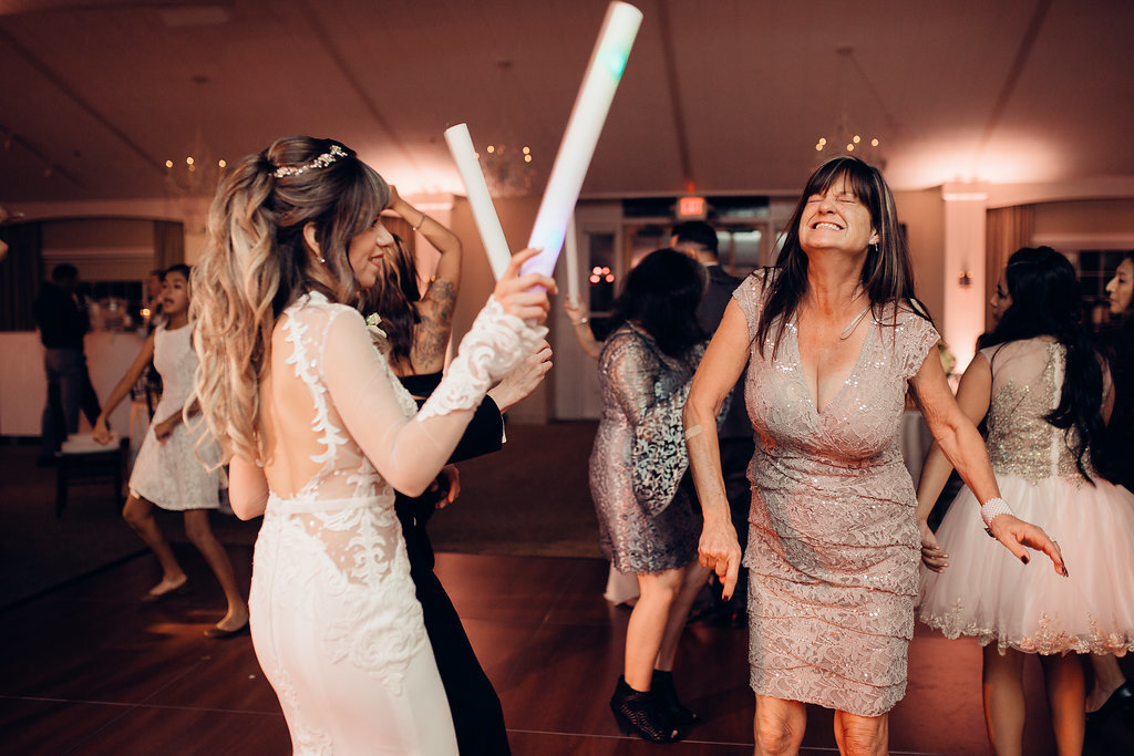 Wedding Photograph Of a Woman Laughing Beside The Bride Holding a Light Stick Los Angeles