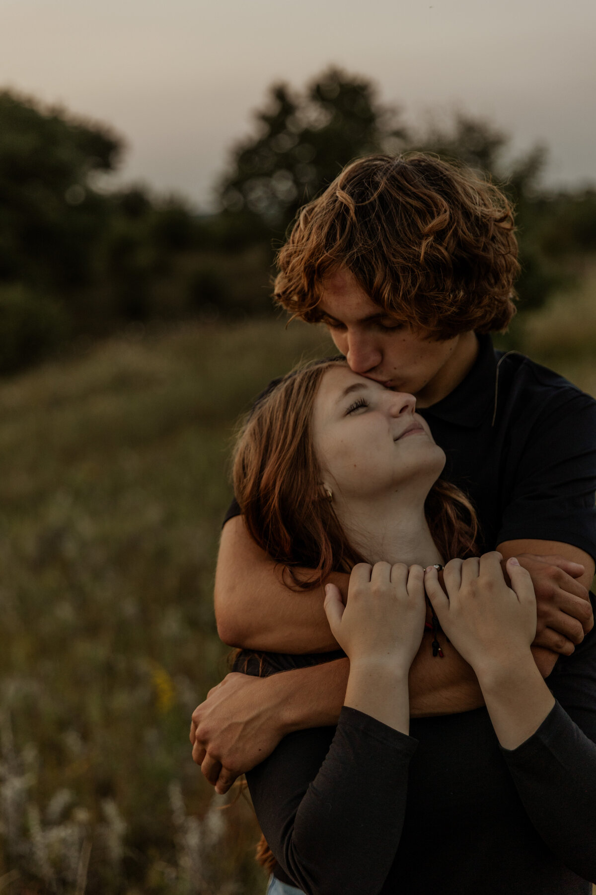 Boyfriend hugging girlfriend and kissing her on the forehead 