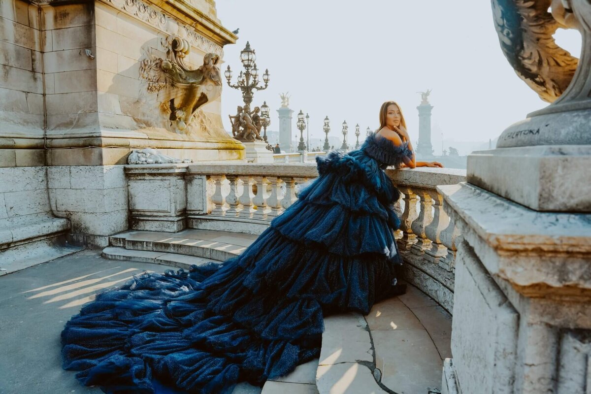 Woman having a photoshoot on a bridge in paris with a black princess gown