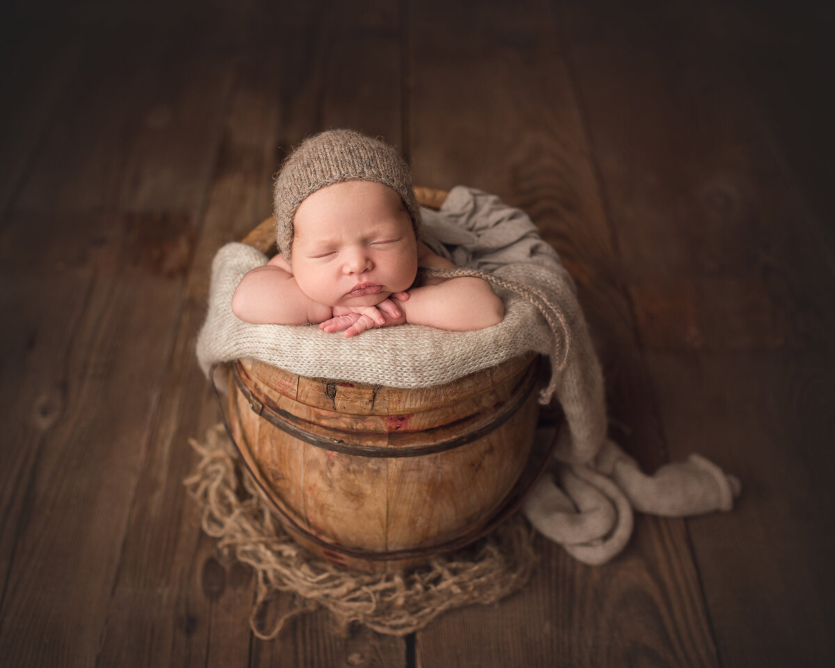 Newborn baby posed safely in bucket, by Katie Anne