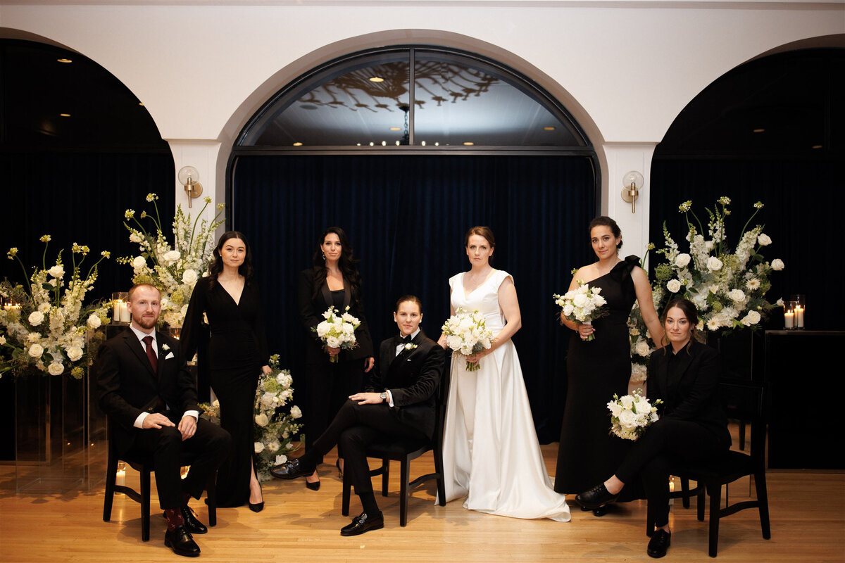 A wedding party pose with flowers for a portrait at the Atwater Club.