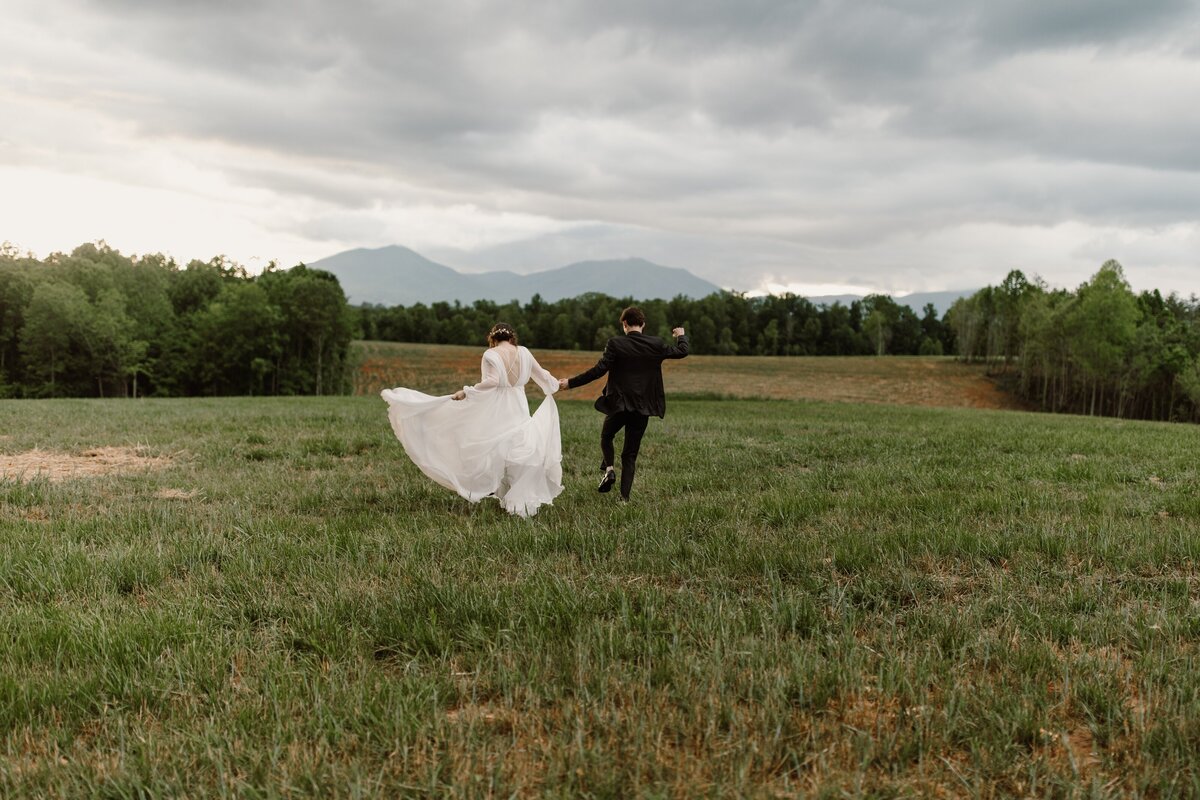 wedding couple skipping through grass field