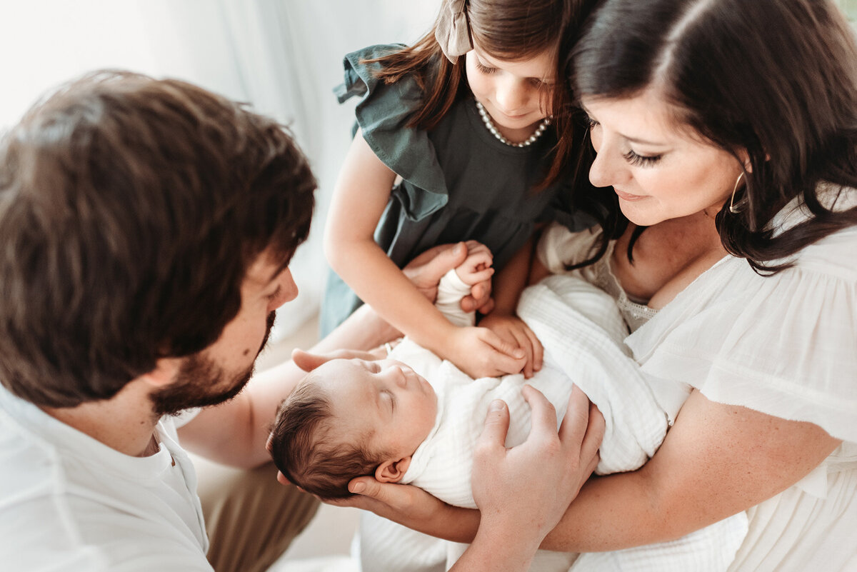 mother holding newborn baby with dad and sister in Denver newborn photo studio