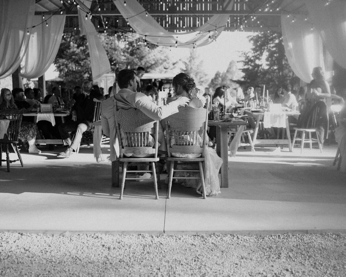 A bride and groom walk hand in hand, captured in a black and white vintage-style photograph, showcasing timeless elegance and nostalgia in Spokane, Washington.