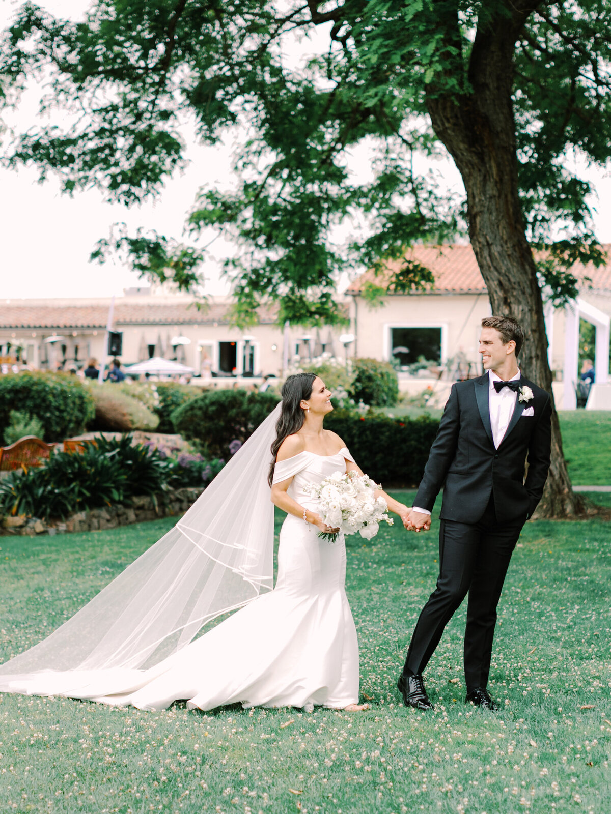 wedding photography of bride and groom walking on grass in front of wedding venue