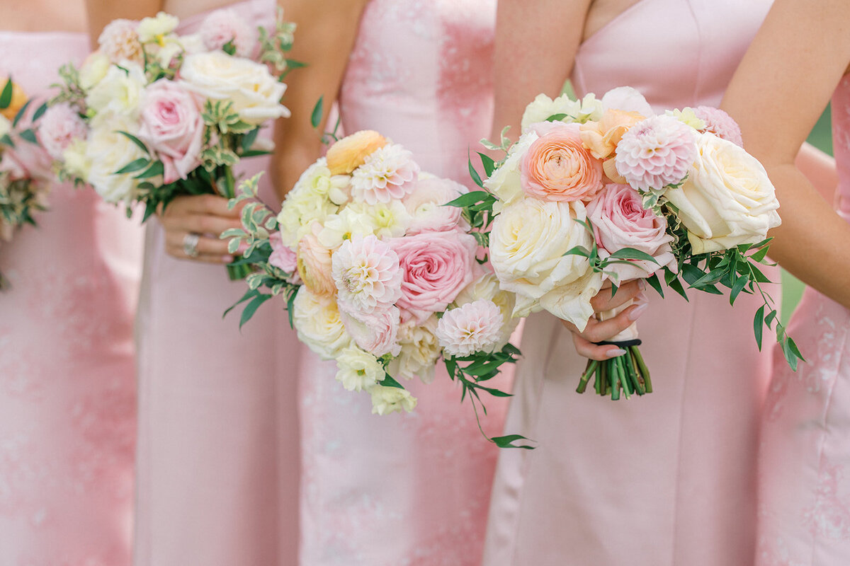 Bridesmaids in light pink dresses holding coloful pink and orange bouquets at wedding at Chattahoochee Towne Club in Atlanta Georgia