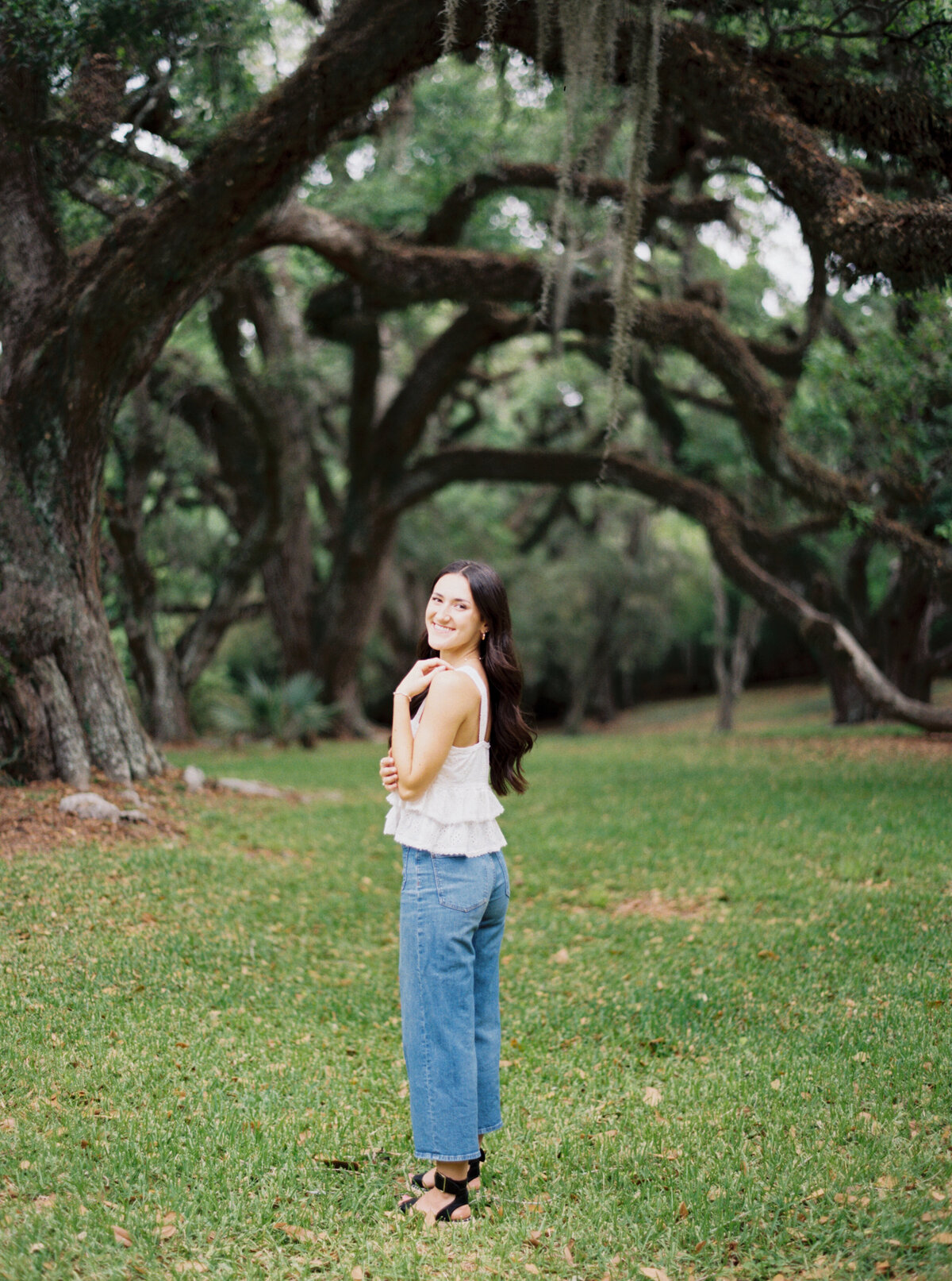 A serene senior portrait surrounded by blossoming flowers at Jungle Gardens, celebrating youth and elegance on film by Morgan Alysse, Louisiana film photographer.
