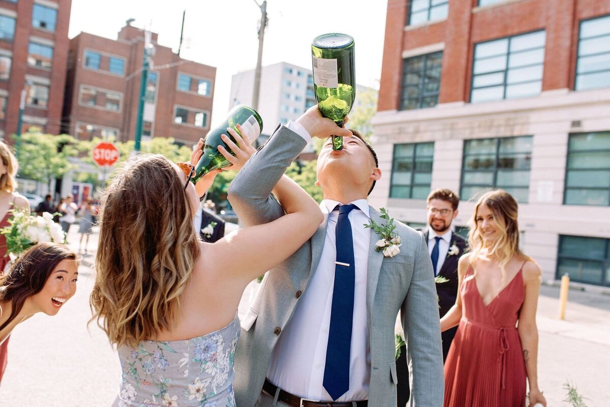 Bride Groom and wedding party celebrate with champagne spray in the downtown Toronto streets happy joyful playful fun spontaneous jacqueline james photography