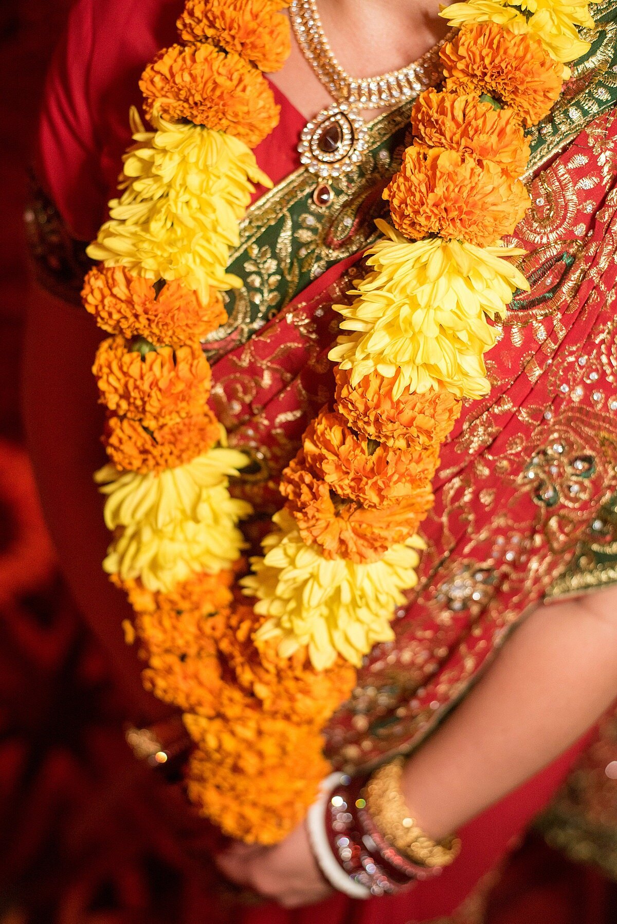 Hindu bride dressed in a red saree wearing Yellow mum and Orange marigold varmala garland for a Nashville Indian Wedding