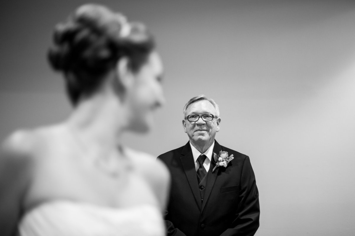 father of bride looking at his daughter getting ready in bridal gown before ceremony at St. Matthews Catholic Church