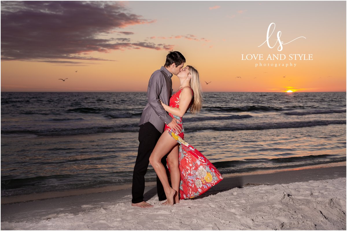 Engaged couple embracing  with a kiss against the Siesta Key sunset taken by Love and Style Photography