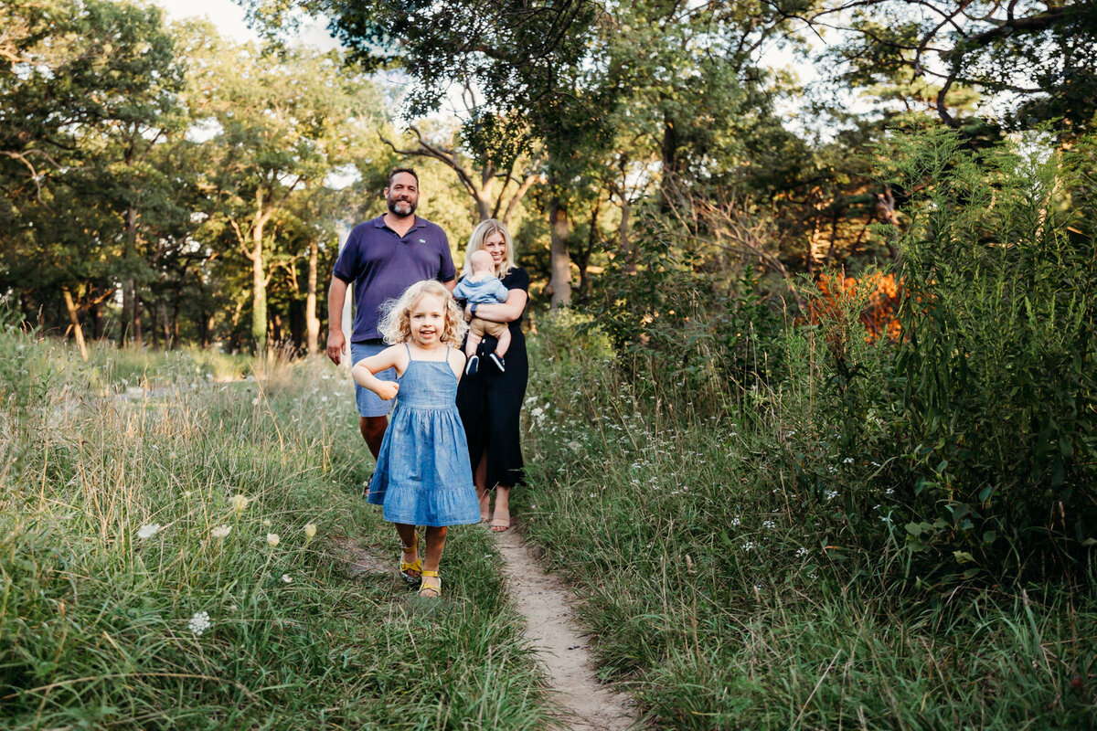 Little girl leading her family through park path during family photos by Claire Binks Photography