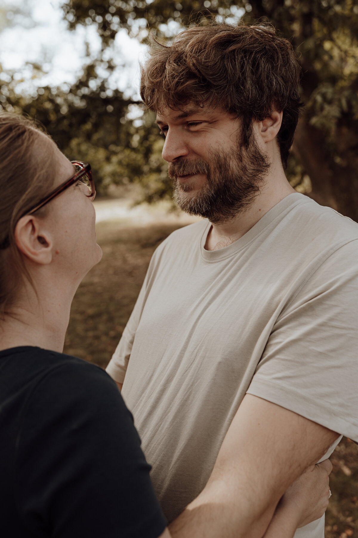 Koppel kijkt elkaar liefdevol aan tijdens loveshoot in het bos