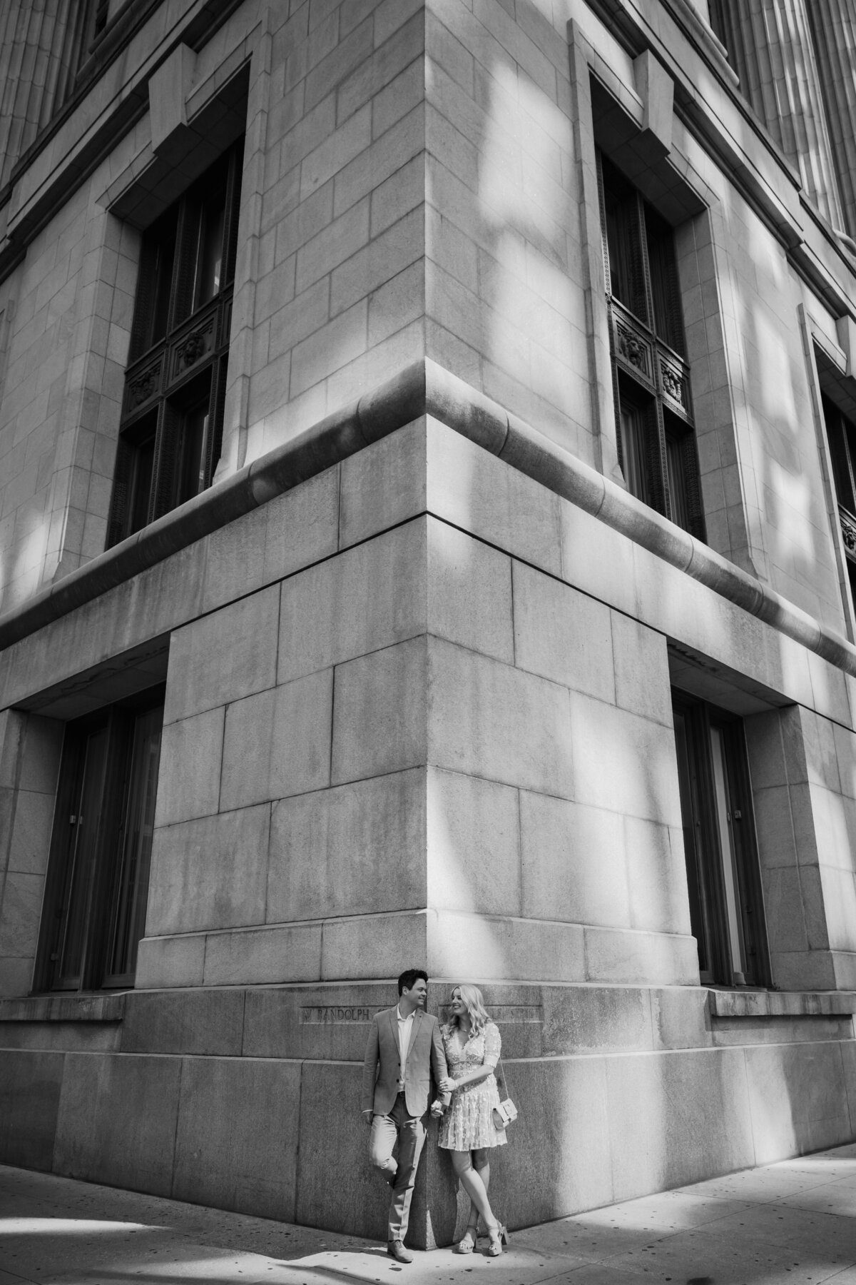 A couple lean against corner wall at Chicago City Hall 