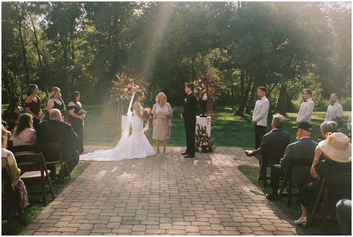 A look down the aisle during an outdoor wedding ceremony with sun beams coming in