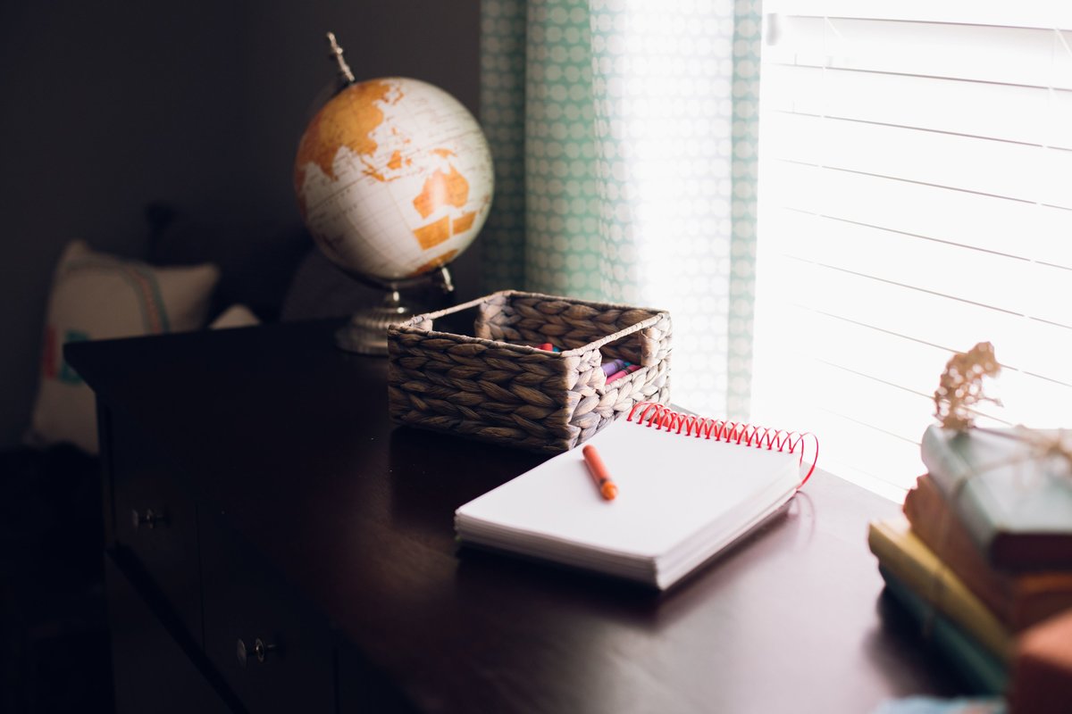 a notepad, globe, and stack of books on a desk