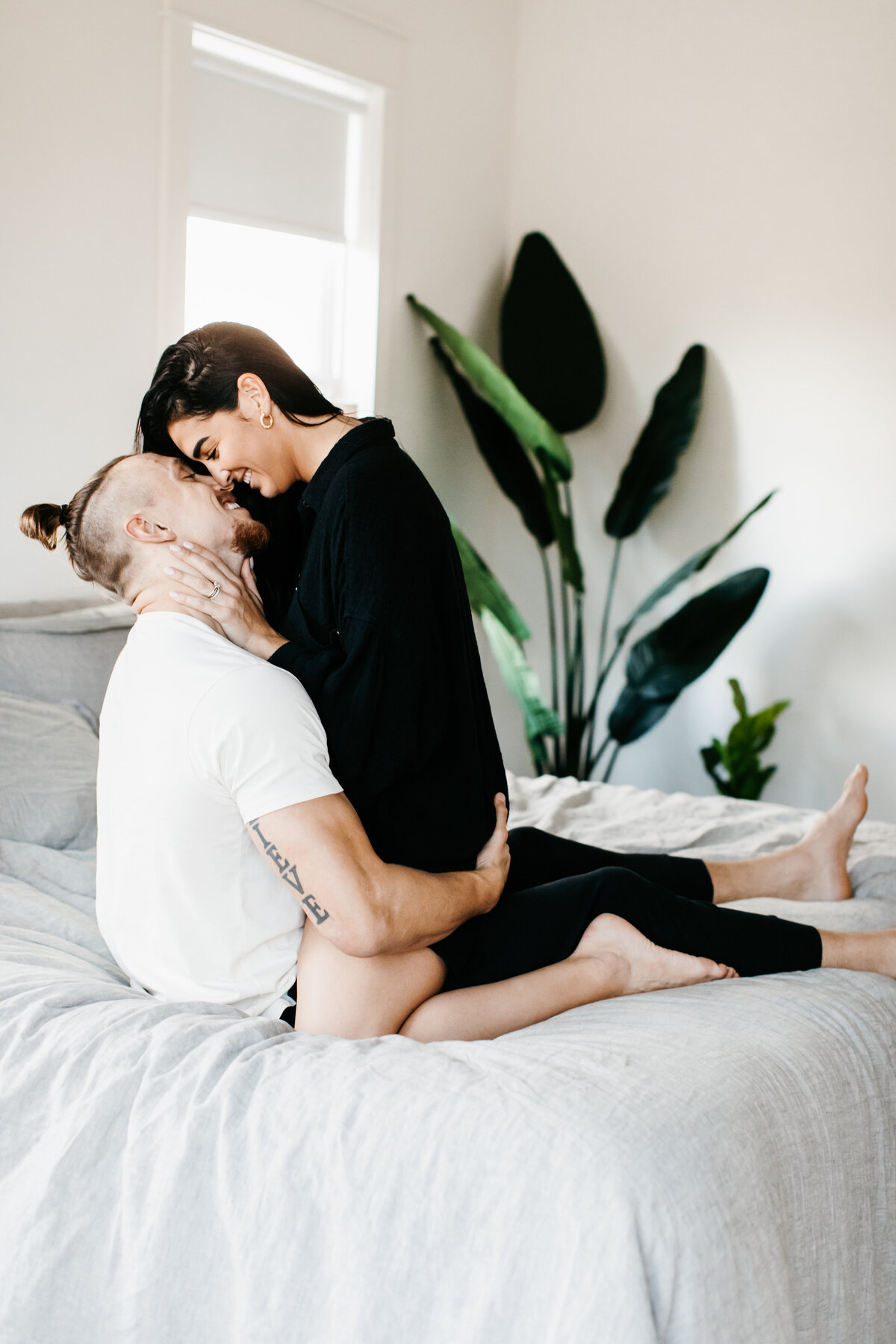 couple kissing each other on a bed in home