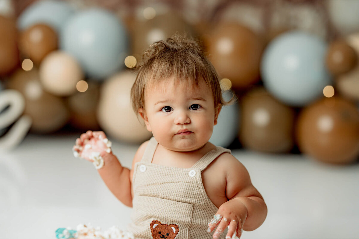 Toddler with cake on hands looking at camera