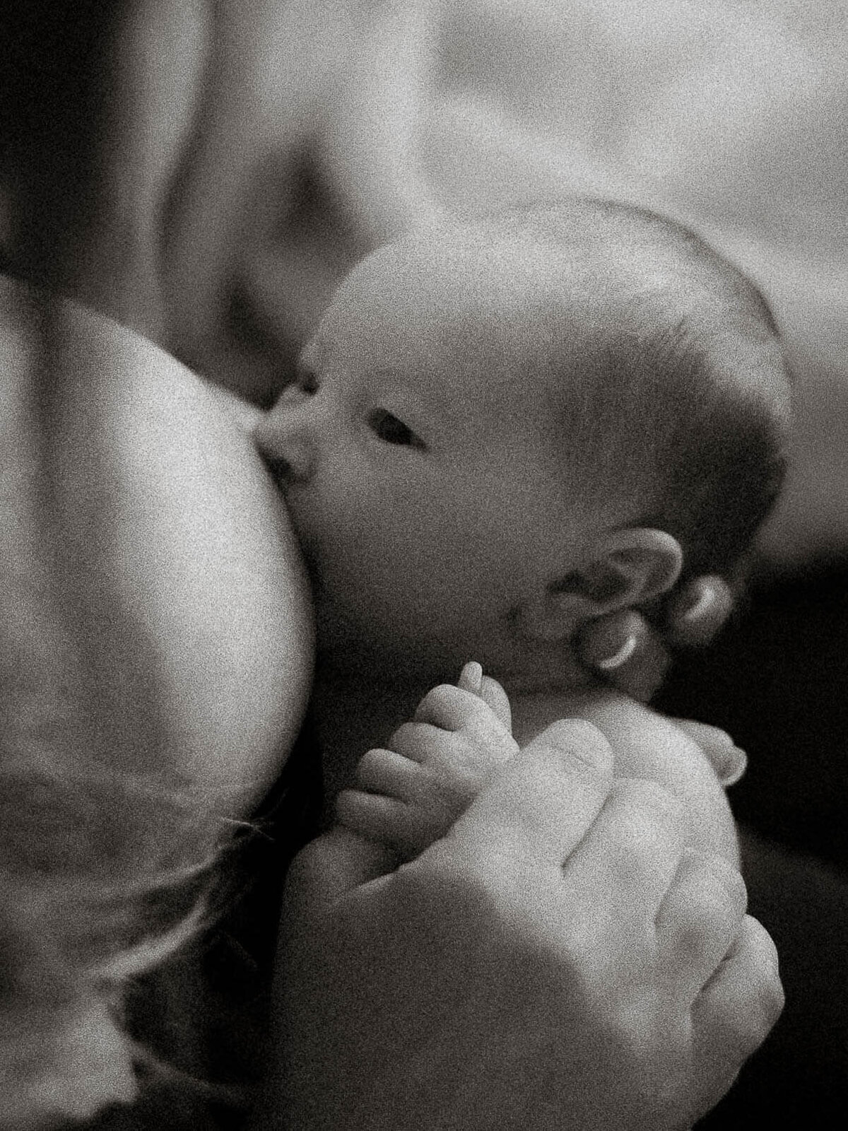 Intimate black and white photo of a mother nursing her newborn during a lifestyle session.