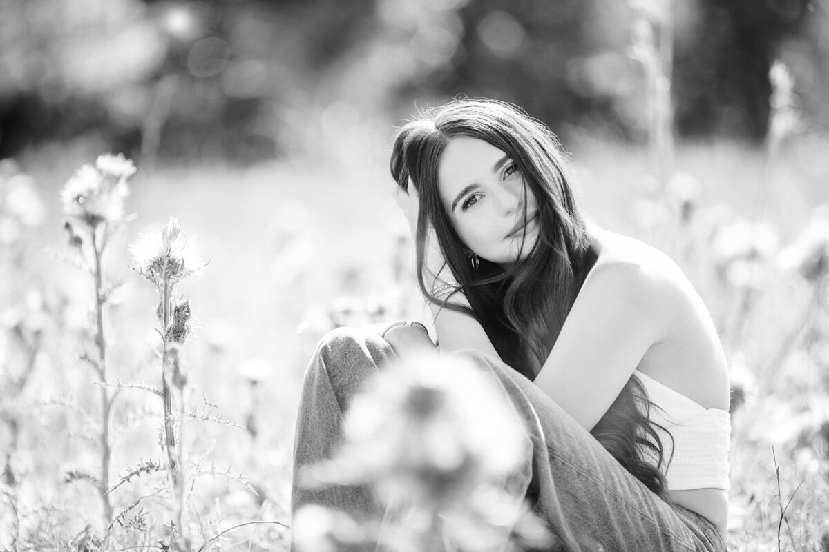 Black and white photo of blonde high school senior laying down by Orlando Graduation Photographer