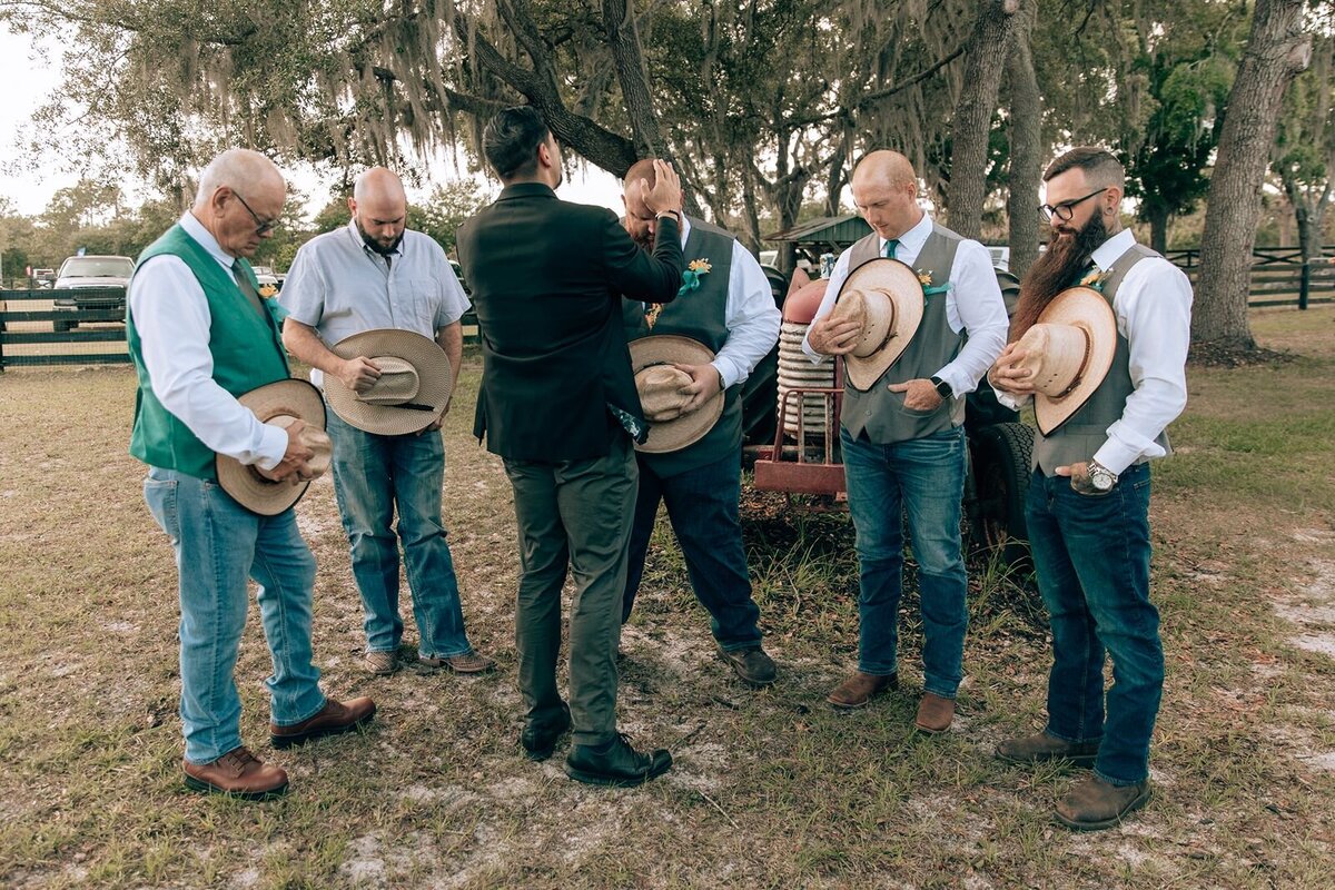 pastor prays with the groom and groomsmen at the farmhouse on 44