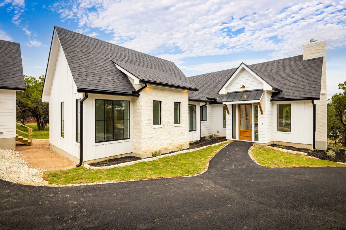 white board and batten house with limestone accents and wood front door