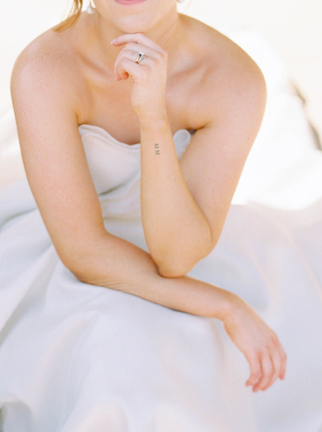 Wedding Photographer RI | A person in a strapless white dress rests their arm on their lap, revealing a small tattoo on the forearm. 