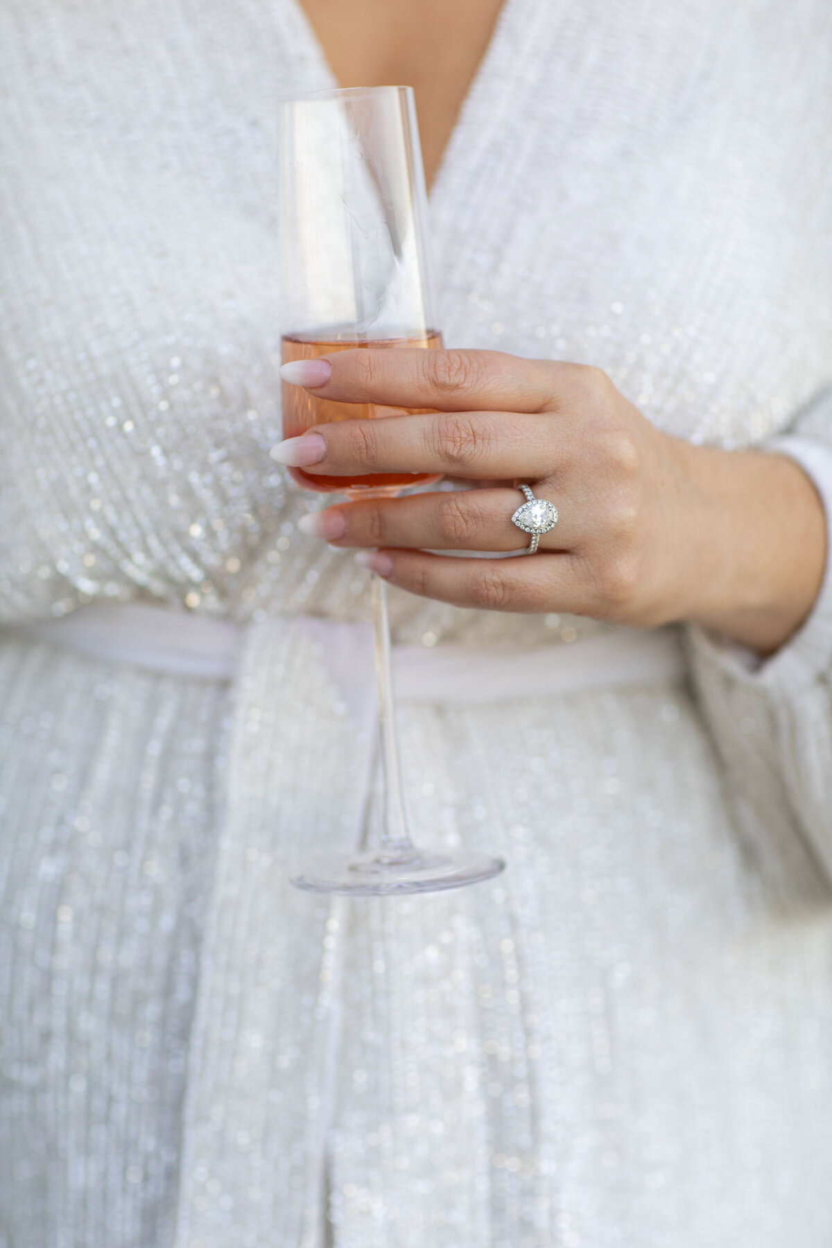 hand of a female with a engagement ring and a glass of champagne