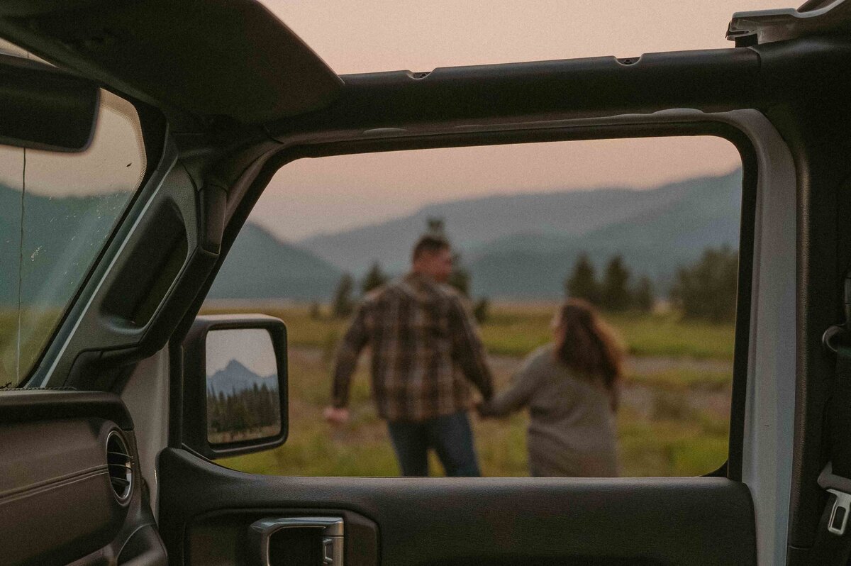 couple running hand in hand through a field
