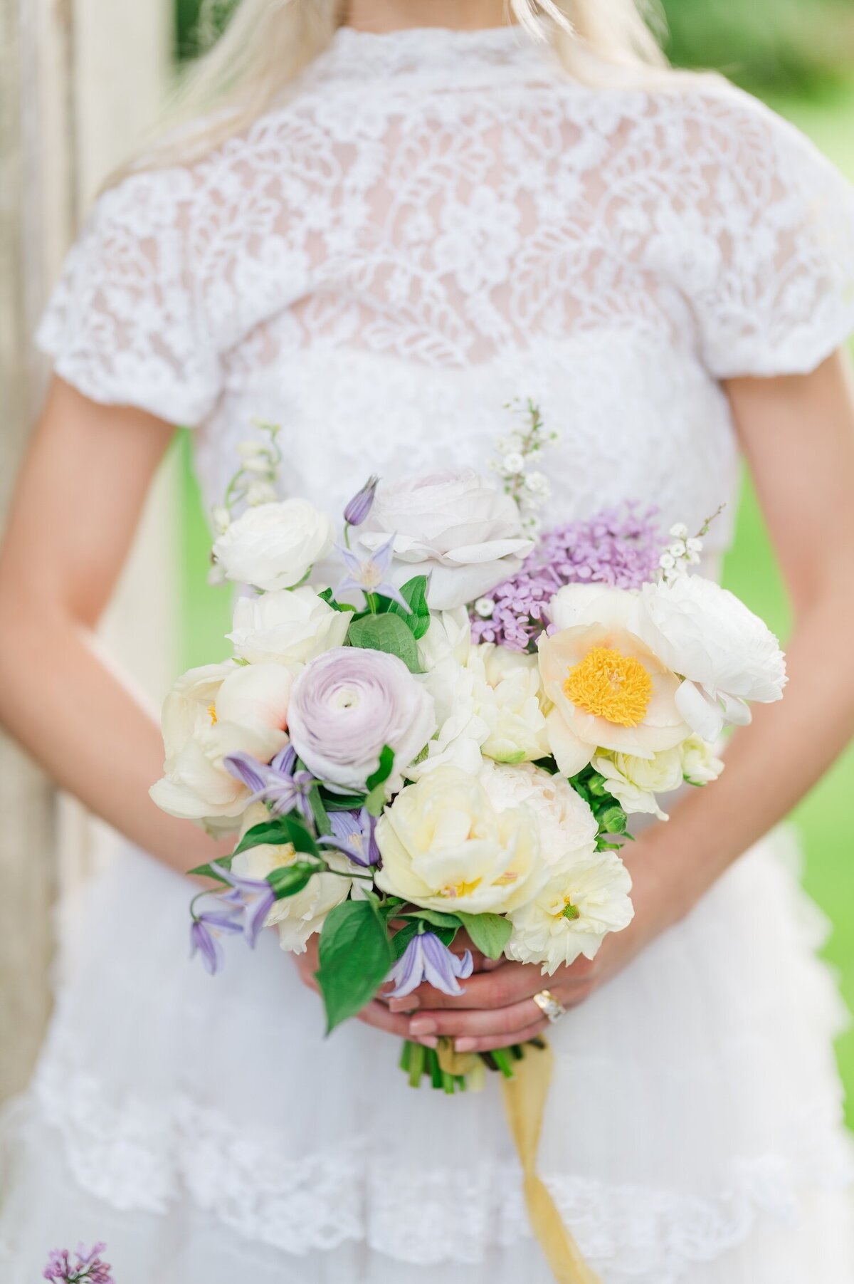 A bride holding a purple, white, and yellow bouquet. 